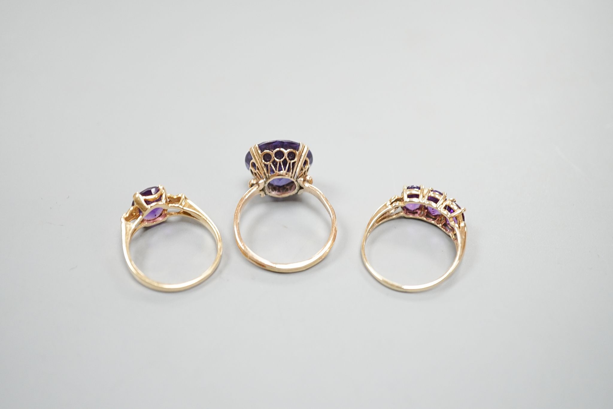 Two modern 14k yellow metal and gem set rings, including amethyst, size N, gross weight 7.4 grams and a similar 10k and three stone amethyst ring, size Q/R, gross 2.3 grams.